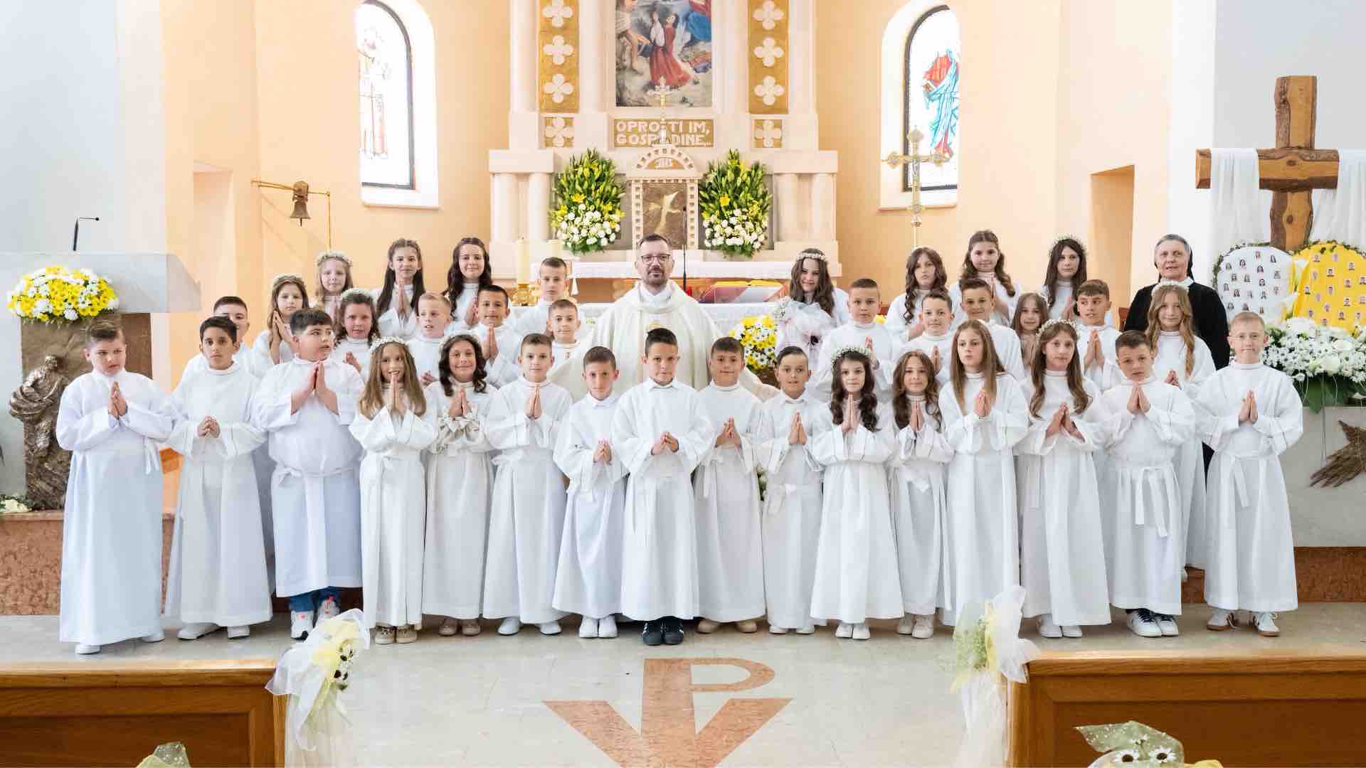 ALT opis fotografije: Prvopričesnici u bijelim haljinama tijekom mise Prve svete pričesti u župi sv. Stjepana Prvomučenika u Čerinu